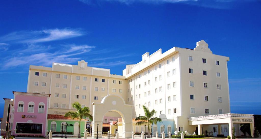 a large white building with palm trees in front of it at Hotel Premier in São Luís