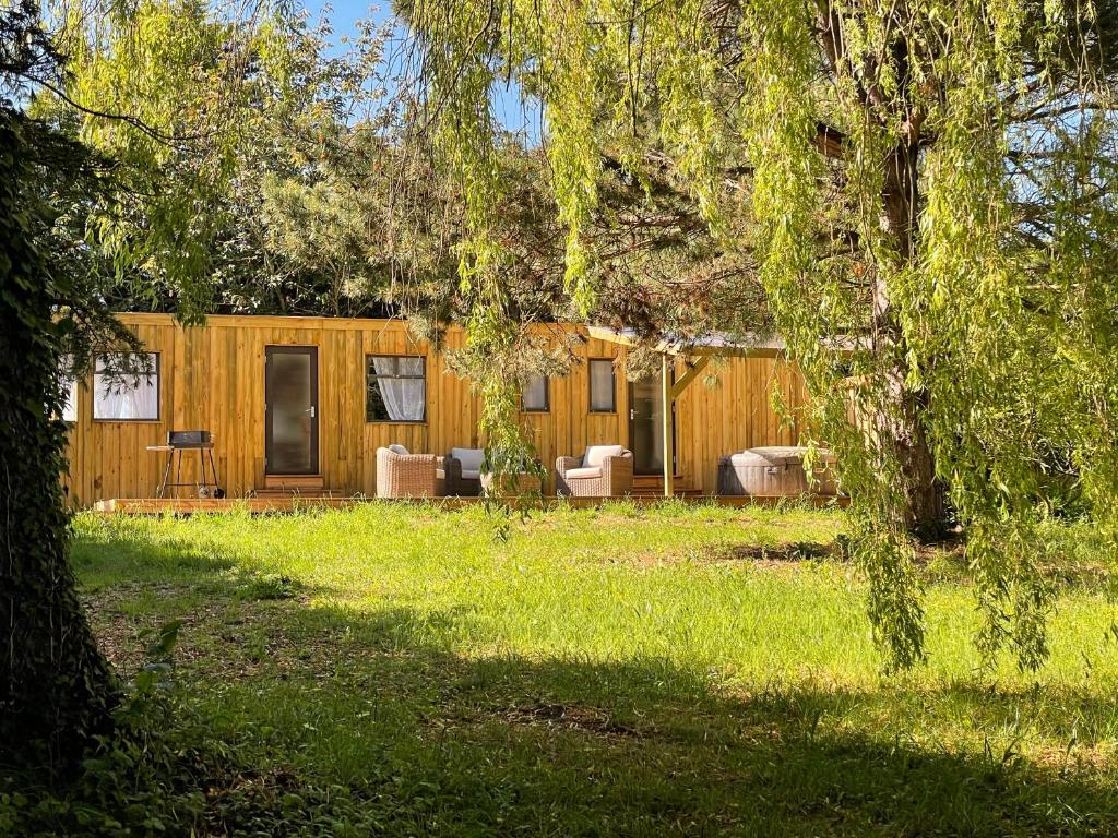 une maison en bois avec des chaises et une table dans une cour dans l'établissement Le Gîte des Oiseaux Un Mobil-Home au Cœur des Champs, à Bellengreville