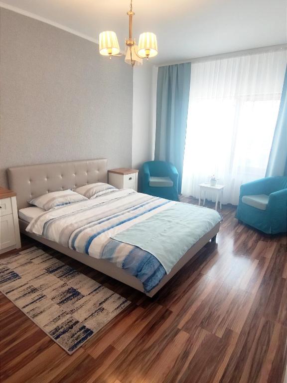 a bedroom with a bed and two blue chairs at Charming apartment in villa Ap2 in Iaşi