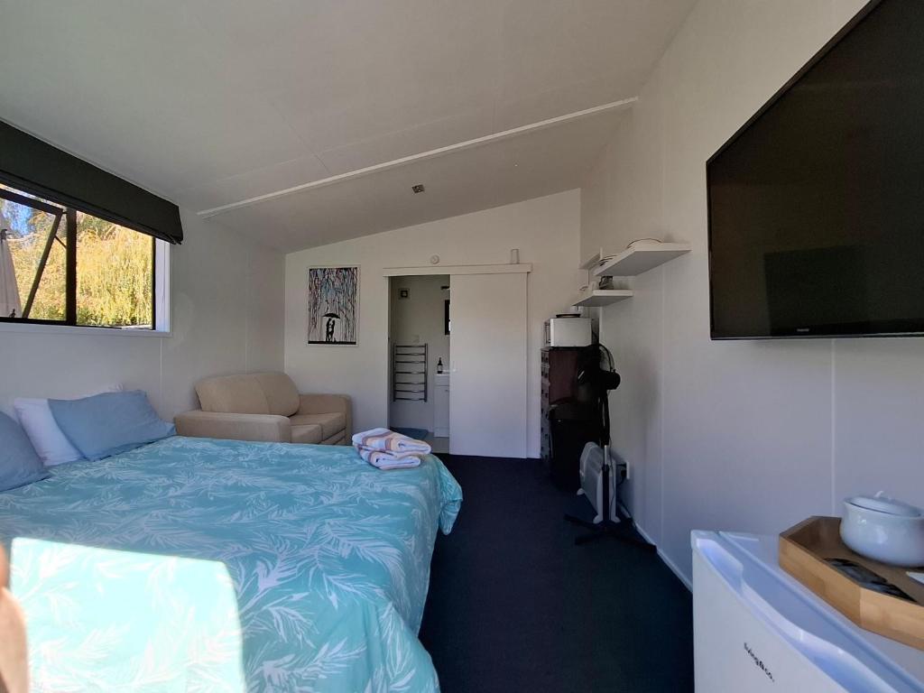 a small bedroom with a bed and a flat screen tv at Shambala in Te Kauwhata