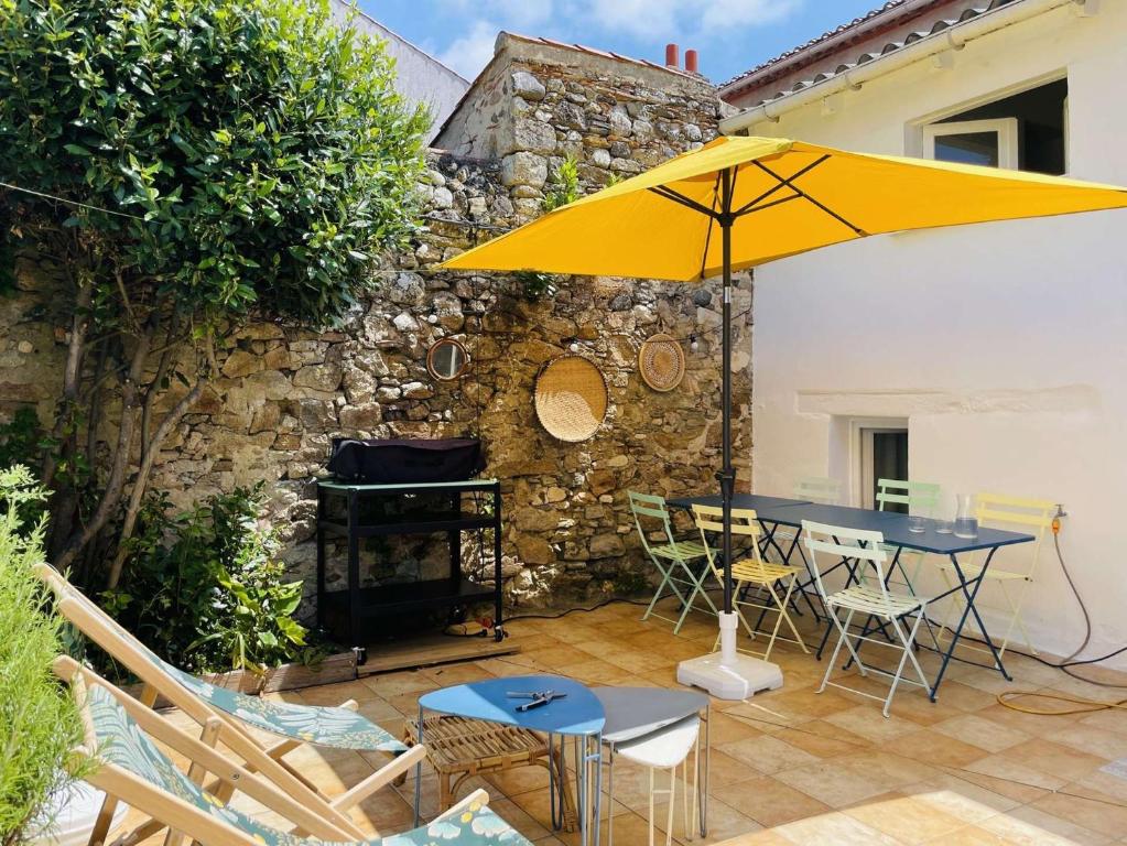 a patio with a table and a yellow umbrella at Palme - Saint Gilles Croix de Vie in Saint-Gilles-Croix-de-Vie