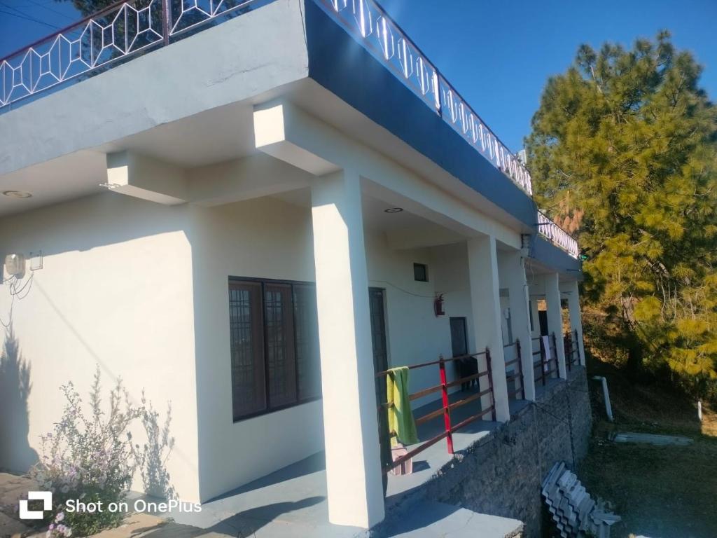 a small white building with a blue roof at MangalMurti Himalyan Homestay in Hawālbāgh
