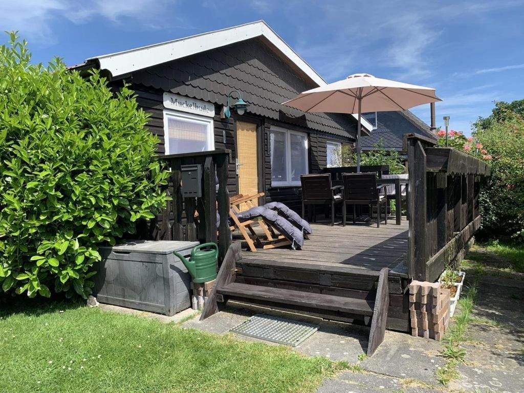 a house with a wooden deck with an umbrella at Ferienhaus Muckelbude in Bedekaspel