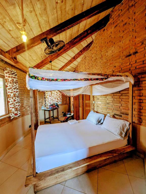 una cama en una habitación con techo de madera en Organica Farmcampus, en Mikindani