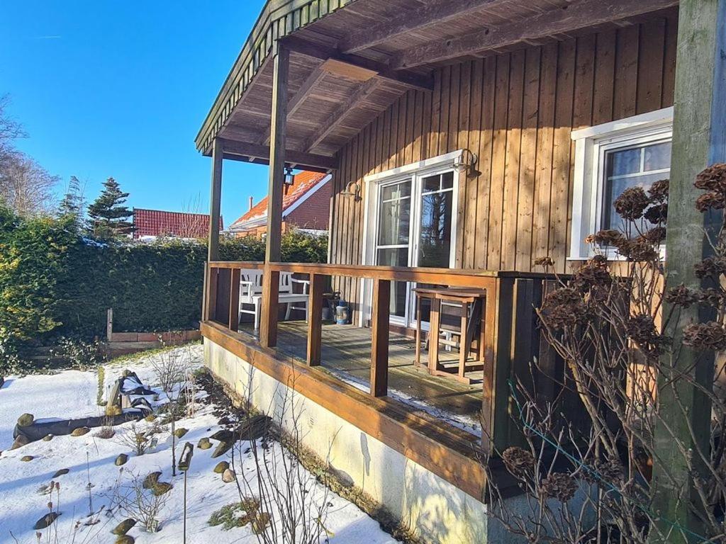 a wooden house with a porch in the snow at Haus Nordwind in Bedekaspel