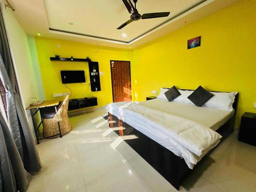 a bedroom with a bed and a yellow wall at Ranghar Homestay Sivasagar in Sivasagar