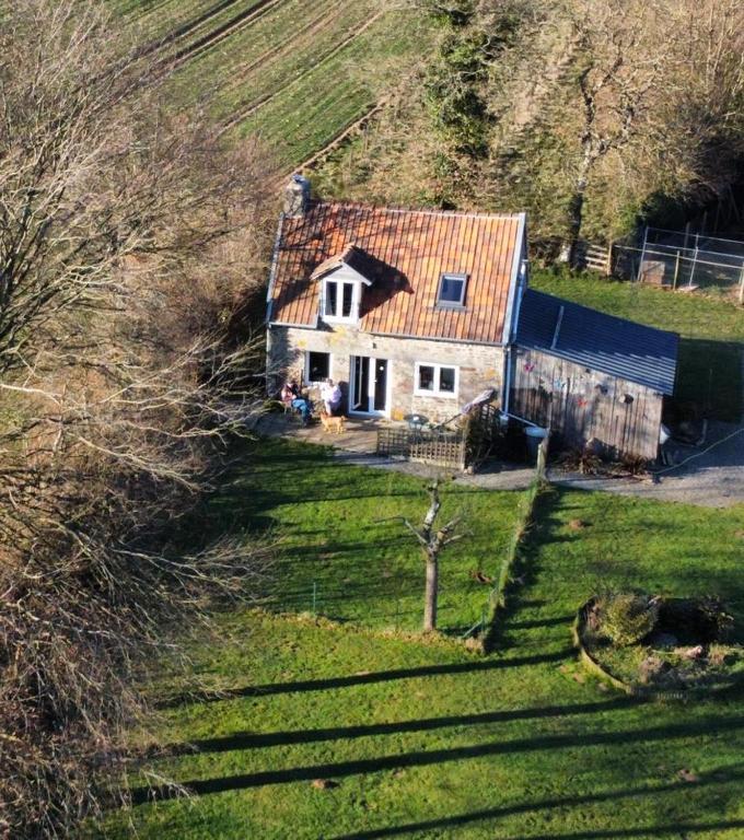une maison avec un toit rouge sur une colline dans l'établissement Ferme de Noyes Cottage, à Sourdeval