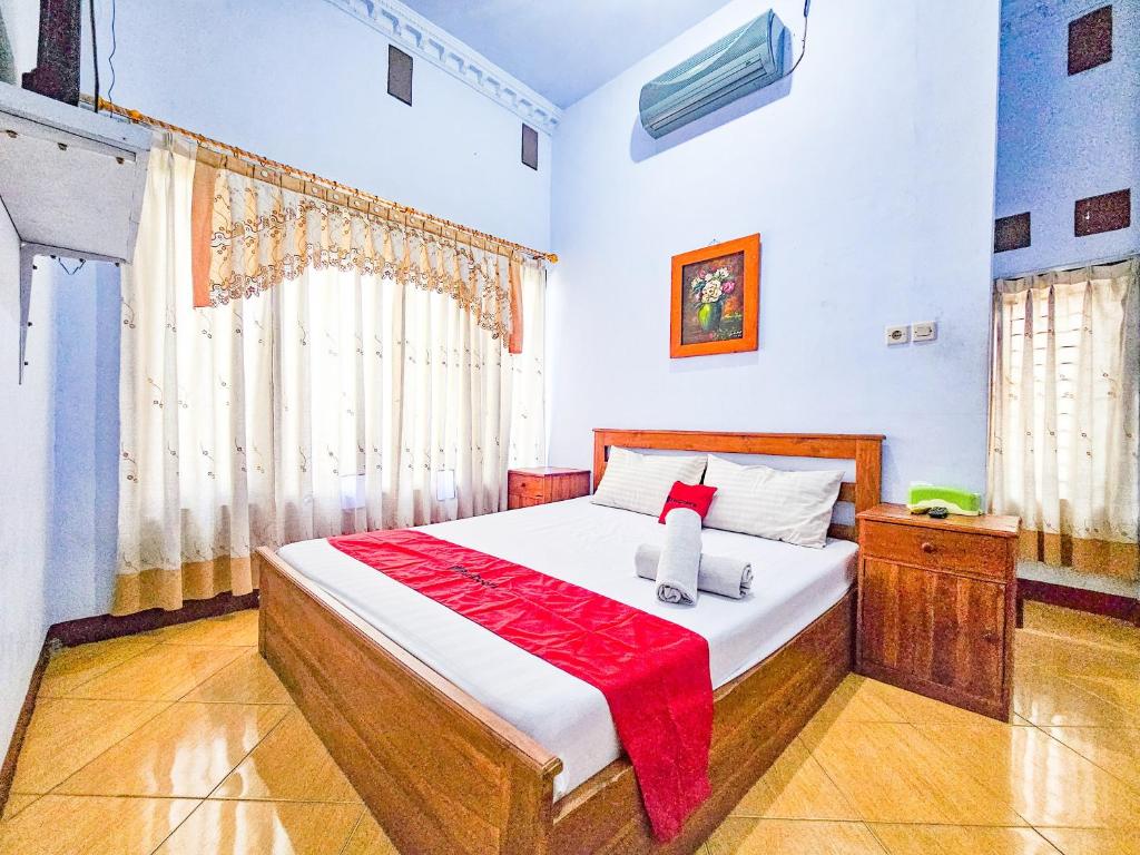ein Schlafzimmer mit einem Bett mit einer roten Decke darauf in der Unterkunft RedDoorz Syariah near Stadion Merdeka Jombang in Peterongan