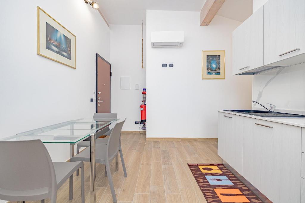 a white kitchen with a glass table and chairs at A7 Moonlight FIERA-RHO-Mi-EXPO-MXP AMPIO&LUMINOSO MONOLOCALE in Cesate
