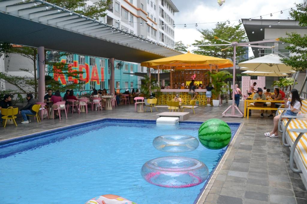 A courtyard pool sits beside outdoor cafés, umbrellas and colorful inflatable floats.