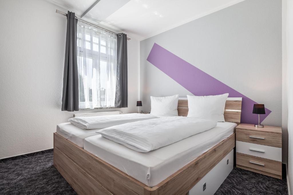 een slaapkamer met een groot bed met een paars hoofdeinde bij Fewo Rosenhof TW 112 in Kühlungsborn