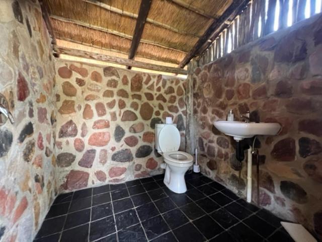 a stone bathroom with a toilet and a sink at Kolobeng Cottages in Gaborone