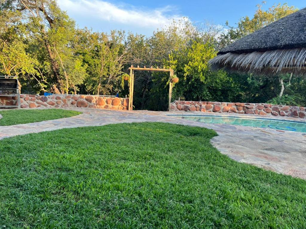 a backyard with a swimming pool and an umbrella at Kolobeng Cottages in Gaborone