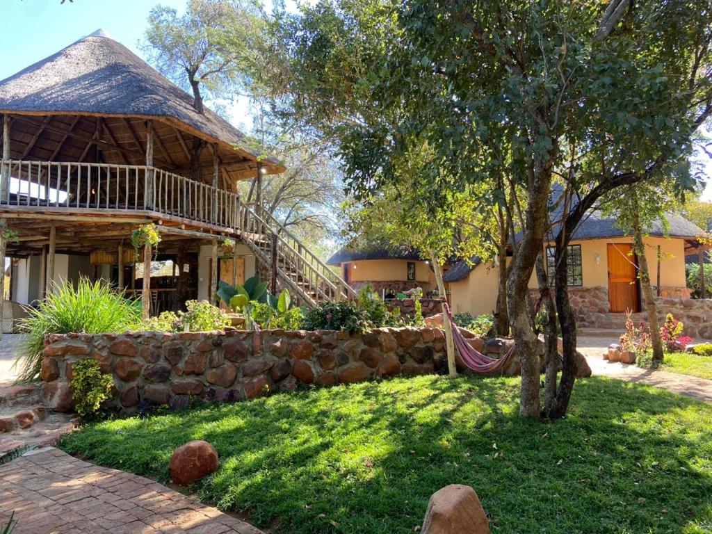 a house with a stone wall and a tree at Kolobeng Cottages in Gaborone