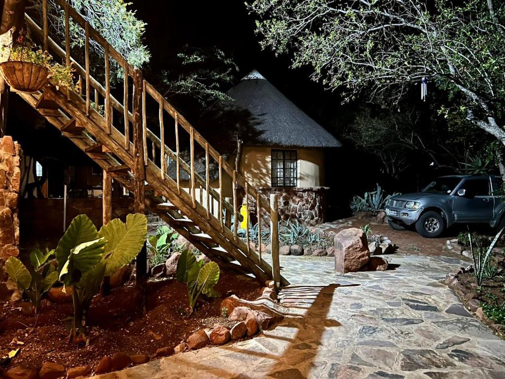 a wooden stairway leading to a house with a car at Kolobeng Cottages in Gaborone