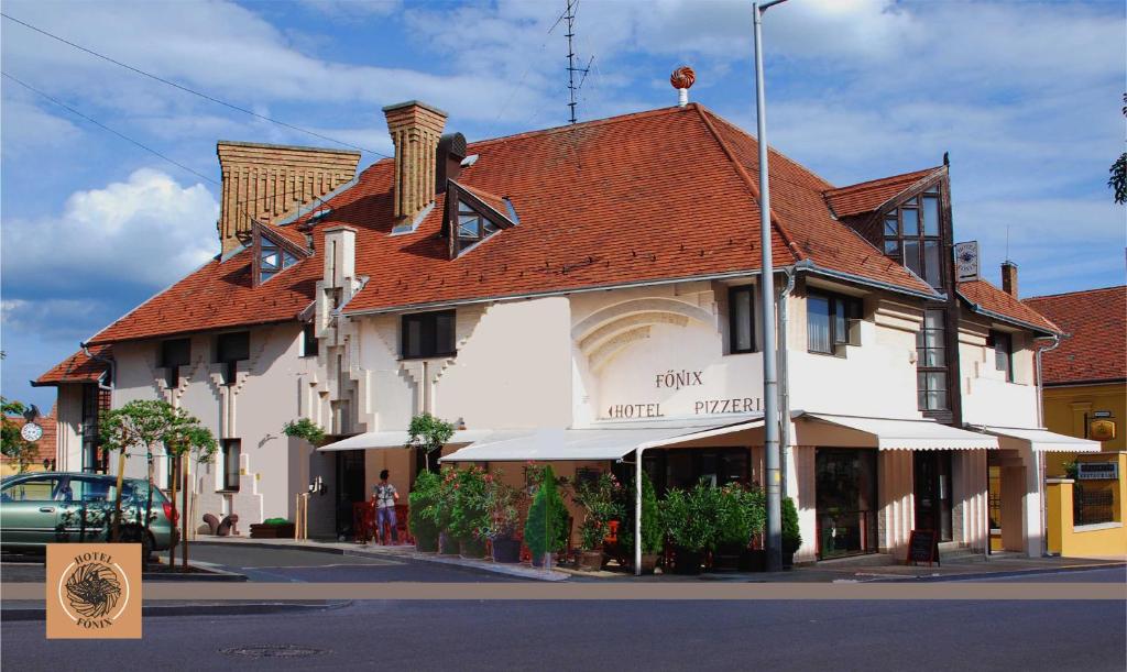 佩奇的住宿－Hotel Főnix，街道上白色的建筑,有红色的屋顶