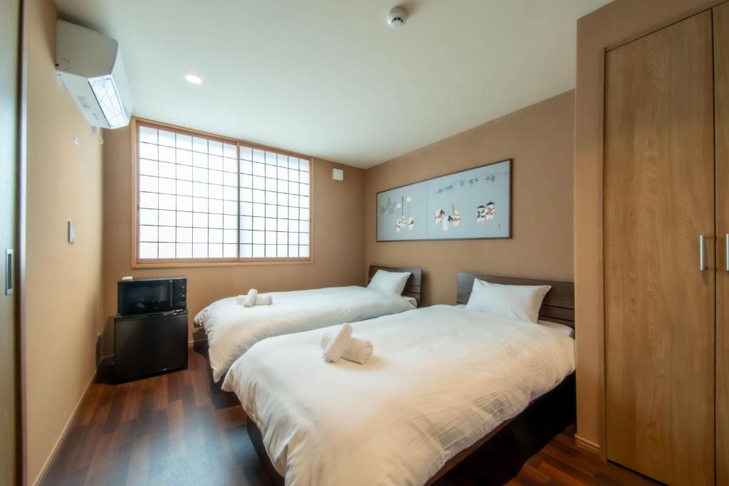 Habitación con 2 camas, TV y ventanas. en The Bonsai Kiyomizu, en Kioto