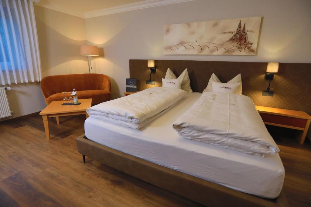 a bedroom with two beds and a chair and a table at Garden & SPA Hotel Das Götzfried in Regensburg