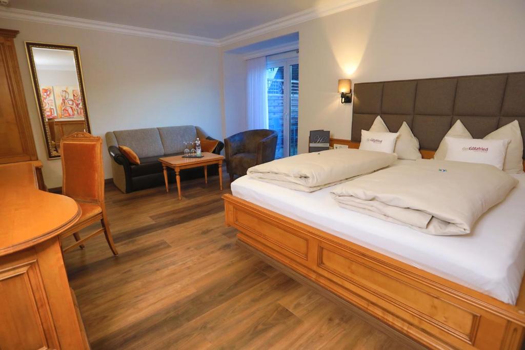a bedroom with a large bed and a living room at Garden & SPA Hotel Das Götzfried in Regensburg
