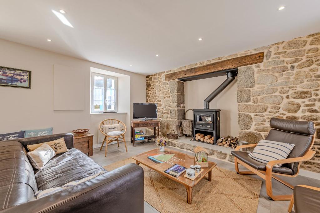 a living room with a couch and a stone fireplace at Ty Line - Plage à 300 m 1 500 m² de jardin in Lampaul-Plouarzel