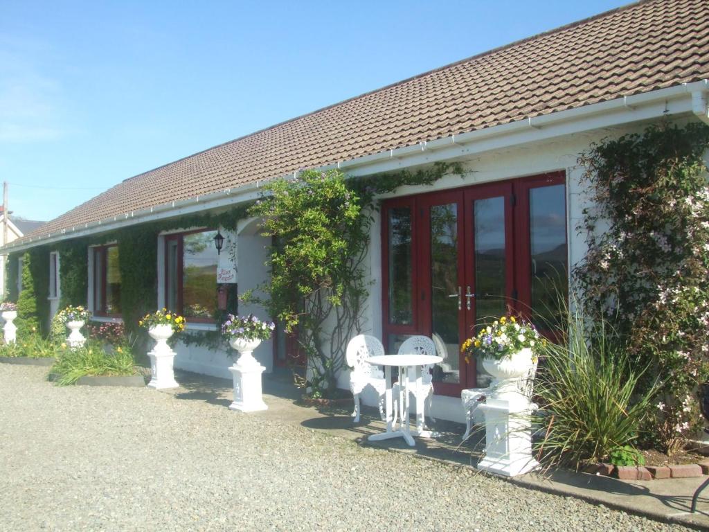 ein Haus mit zwei weißen Stühlen und einem Tisch in der Unterkunft River Meadows B&B in Kenmare