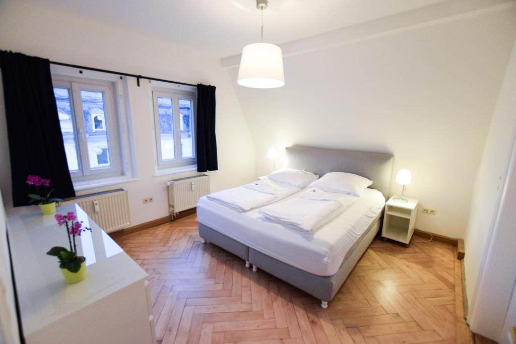 a bedroom with a white bed and two windows at Ferienwohnung Ratisbona in Regensburg