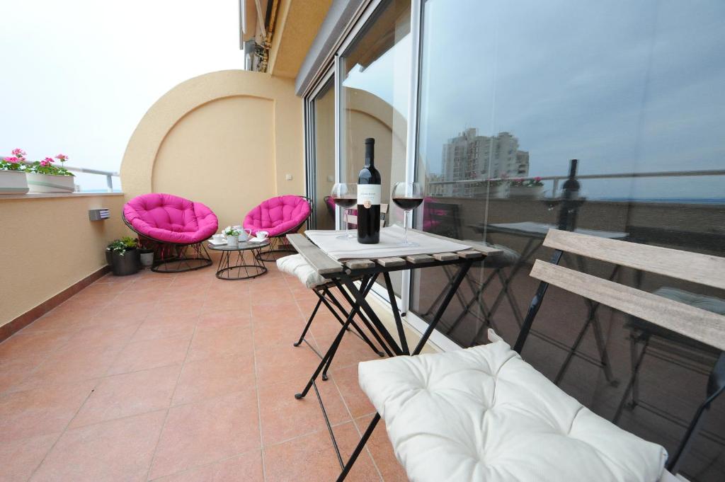 a balcony with pink chairs and a table with wine bottles at Apartment Gold Plus in Split