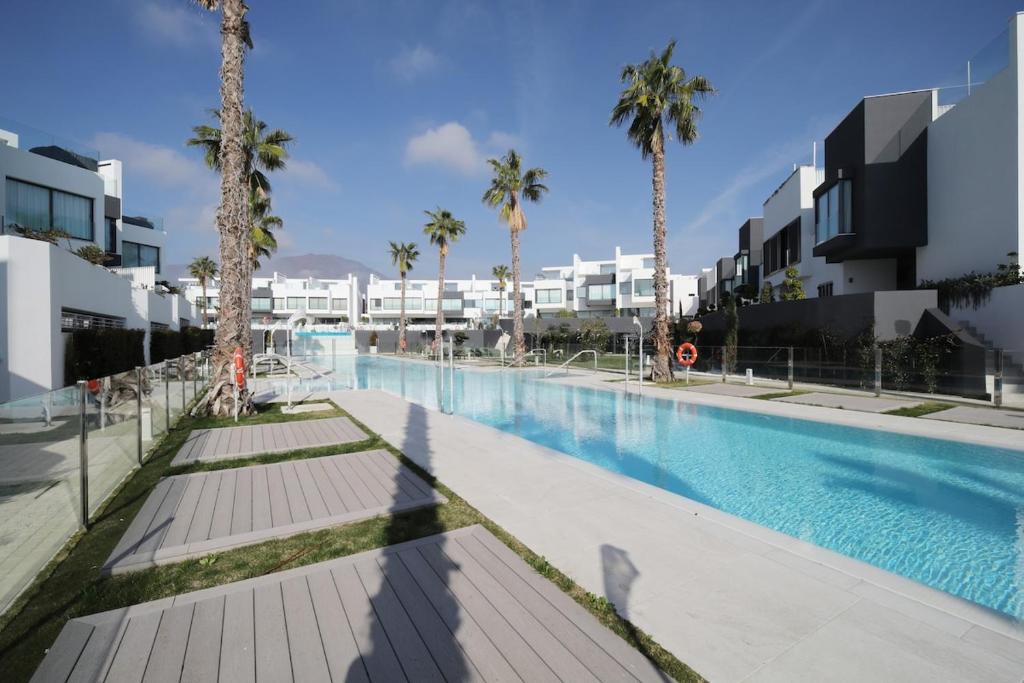 Una gran piscina con palmeras y edificios. en The Next Gen Villa, en Estepona