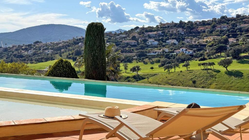 - une piscine avec deux chaises longues et une montagne dans l'établissement Villa Les Amandiers, à Sainte-Maxime