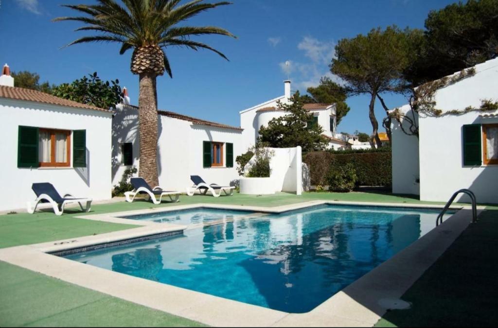 a swimming pool in front of a house with a palm tree at Angelinas Villas 2 Hab con Piscina in Cala Blanca