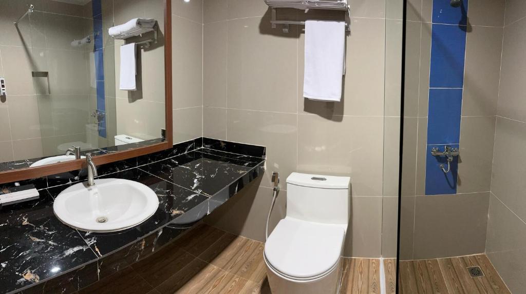 a bathroom with a white toilet and a sink at Arraudah Hotel Syari'ah in Paringin