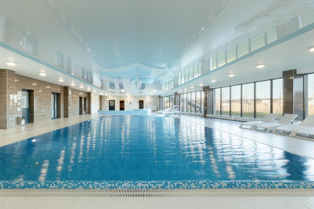 a large swimming pool in a building with windows at Luxury Apartment 23 basen i sauna D&D Apartments in Dziwnów