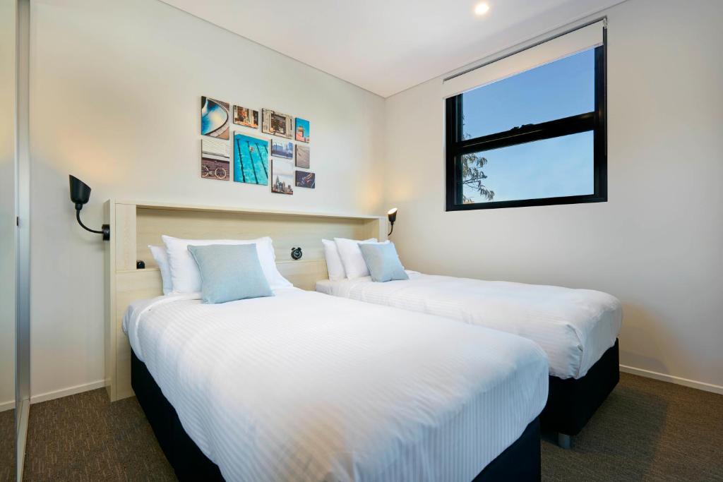 two beds in a room with a window at Veriu Camperdown in Sydney