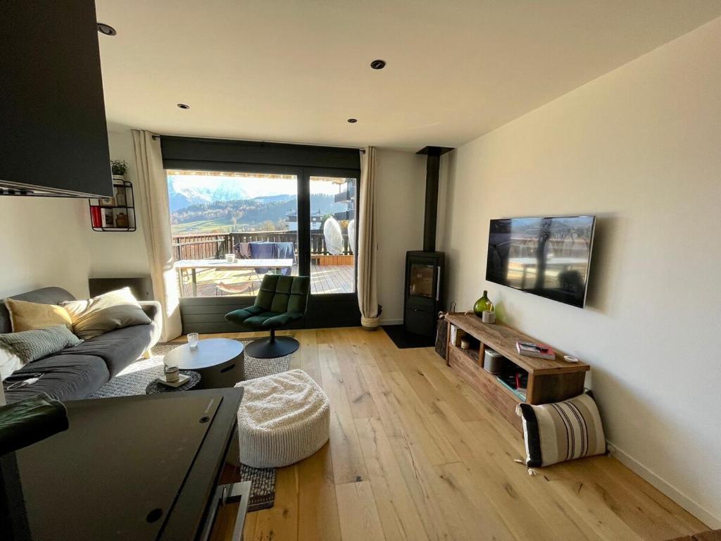 un salon avec un canapé et une télévision dans l'établissement Cocon alpin, à Cordon