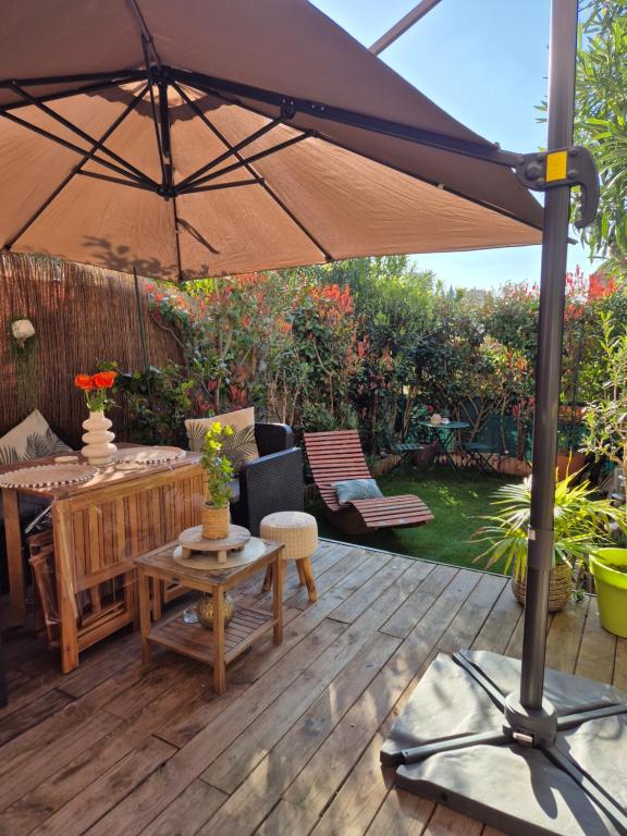 een patio met een parasol op een houten terras bij Studio cocooning - Terrasse - Jardin - Piscine in Menton