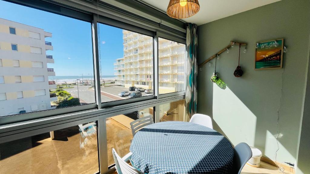 une table et des chaises dans une pièce avec une grande fenêtre dans l'établissement Mer et pins, refait à neuf, à Saint-Jean-de-Monts