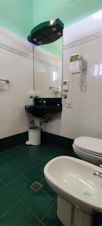 a bathroom with a sink and a toilet and a mirror at Hotel Baffo Rosso in Alba Adriatica