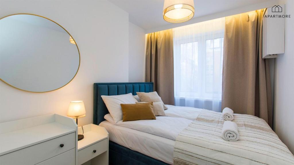 Neat bedroom with teal upholstered headboard, bedside lamp, decorative pillows and rolled towels.