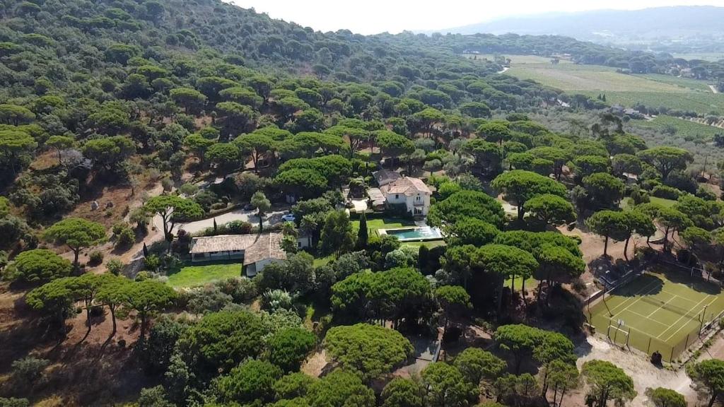 - une vue aérienne sur une maison avec un court de tennis et des arbres dans l'établissement Le Mas Ramatuelle, à Ramatuelle