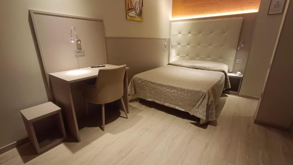 a small bedroom with a bed and a desk at Hotel Baffo Rosso in Alba Adriatica