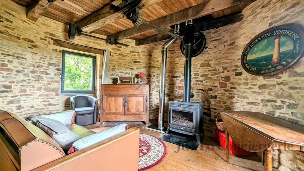 - un salon avec un canapé et un poêle à bois dans l'établissement So Romantic - Le Moulin de Camargois, à Avessac