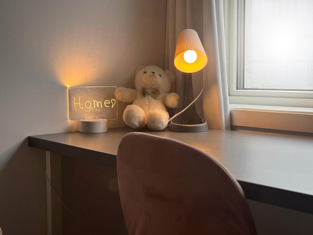 a stuffed teddy bear sitting on a desk with a lamp at Apartment near city center with free parking in Bergen