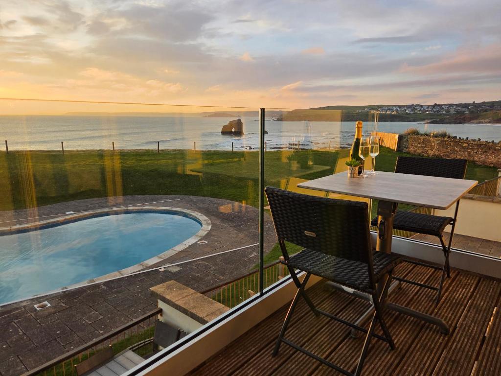 a balcony with a table and chairs and a view of the ocean at 7 Ocean's Edge in Kingsbridge
