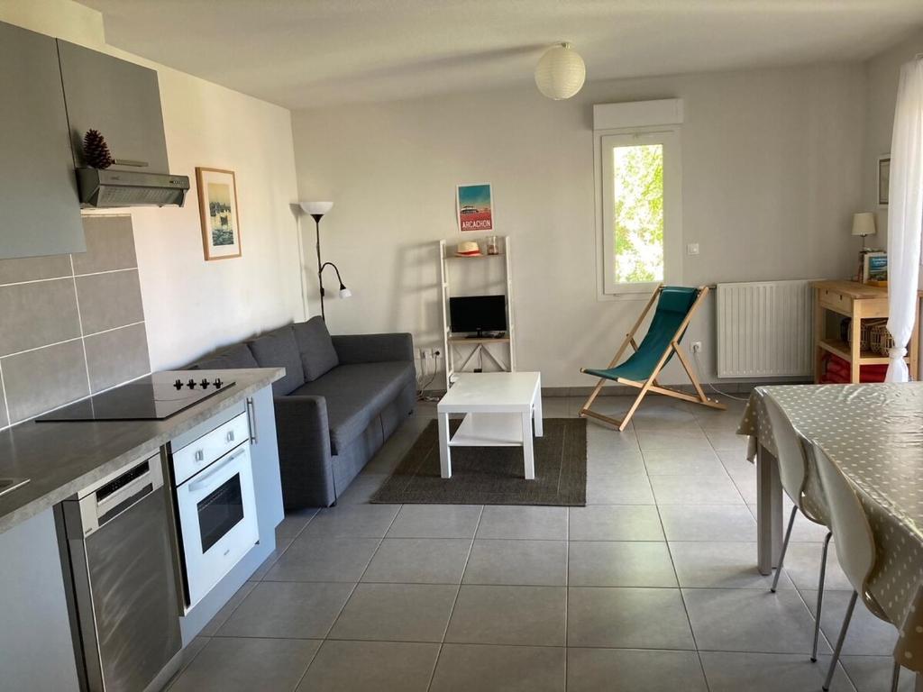 une cuisine et un salon avec un canapé et une table dans l'établissement Appartement Gujan Mestras premier étage, à Gujan-Mestras