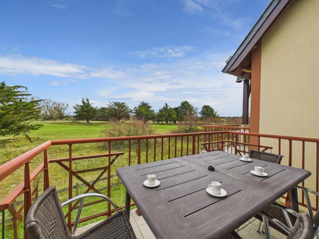 - une table en bois sur un balcon avec des chaises et des tasses à café dans l'établissement Vue sur le Golf de Fréhel - Piscine chauffée, à Fréhel
