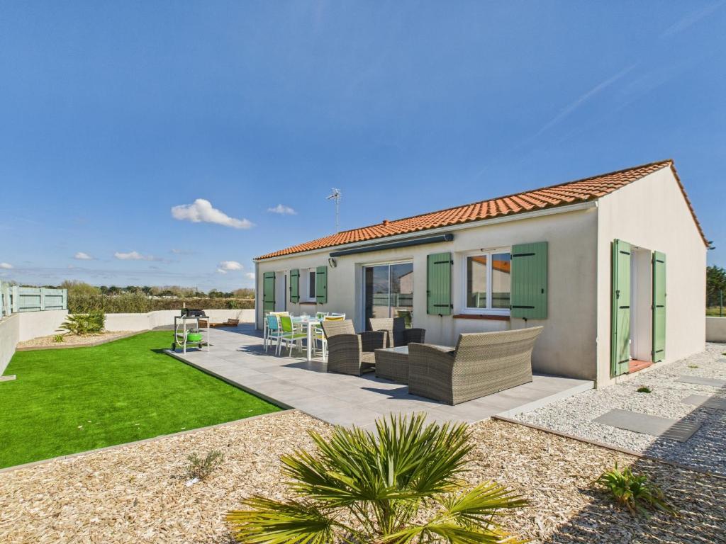 une villa avec une terrasse et une pelouse dans l'établissement Jolie maison avec extérieur pour 6 proche mer, à Saint-Hilaire-de-Riez