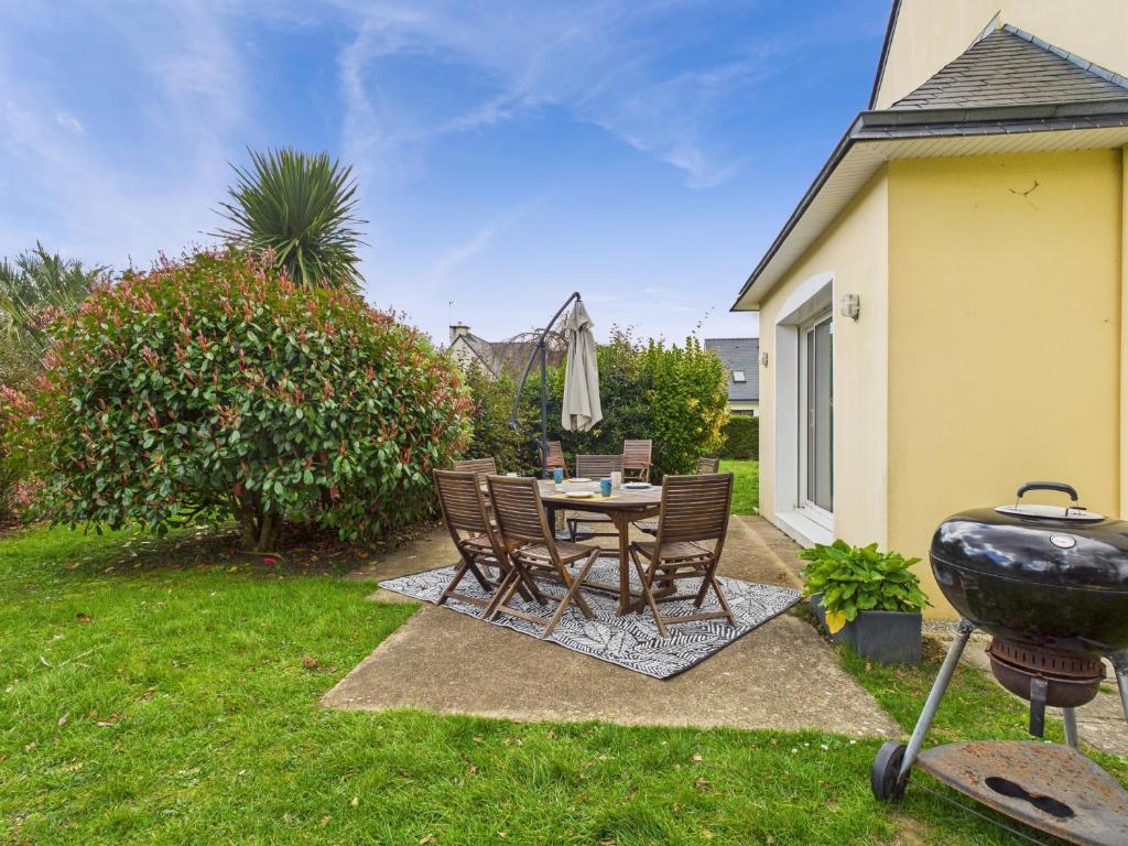 une arrière-cour avec une table, des chaises et un grill dans l'établissement Maison avec terrasse et jardin pour 6 - Bénodet, à Bénodet