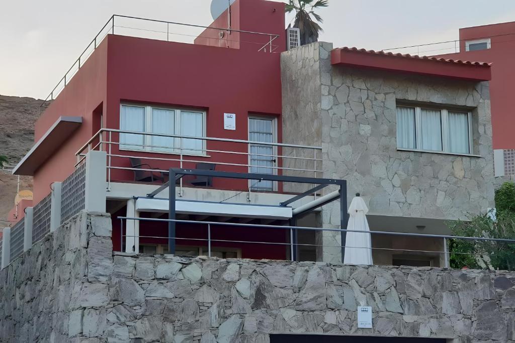 ein rotes Haus mit einer Steinmauer davor in der Unterkunft Pure luxury and comfort La Oliva in La Playa de Tauro