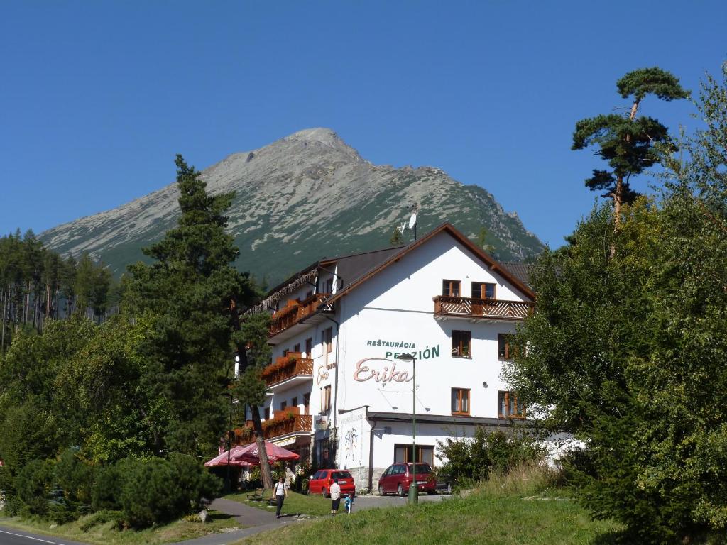 a large white building with a mountain in the background at Erika penzión in Vysoké Tatry