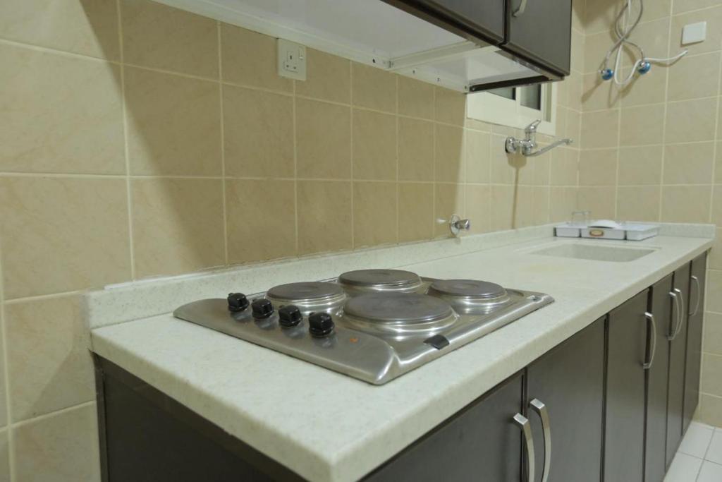 a kitchen counter with a stove and a sink at شقق اجنحة الروزا للشقق المخدومة in Buraydah